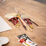 Zestaw pędzli i przyborów malarskich leżących na stole podczas warsztatów „Jak malujemy swój wizerunek?” organizowanych przez Twój StartUp.