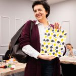 Uśmiechnięta uczestniczka warsztatów prezentująca swoje kolorowe malarskie dzieło podczas wydarzenia „Jak malujemy swój wizerunek?” organizowanego przez Twój StartUp.